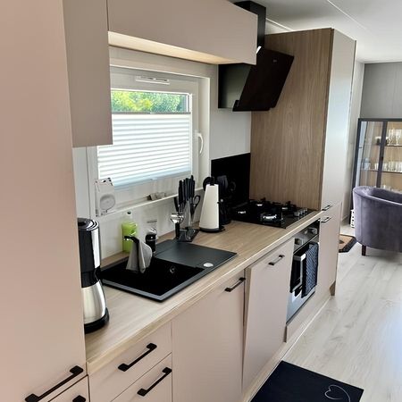 Funktionale Küche im modernen Heim Chalet, ausgestattet mit Spüle, Mikrowelle, Kaffeemaschine, Herd und Ofen für den Alltag.