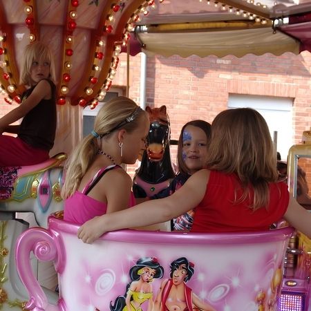 Ein buntes, rosa Karussell mit Kindern, das auf einer Veranstaltung für Unterhaltung und Freude sorgt.