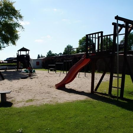 Ein Spielplatz mit einer Rutsche und Schaukeln, ideal für Kinder zum Spielen und Entspannen im Freien.