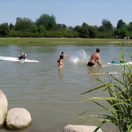 Eine Gruppe von Menschen im Wasser, die gemeinsam schwimmt und sich amüsiert, umgeben von einer sonnigen Umgebung.