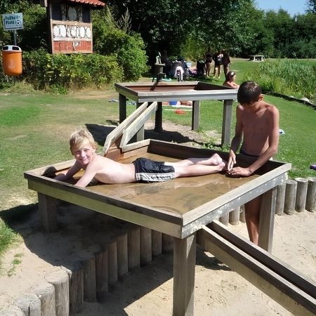 Zwei Jungen spielen auf einem Wasserspiel.